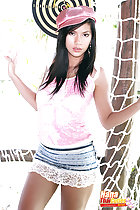 Standing in front of netting wearing hat in pink top wearing short skirt